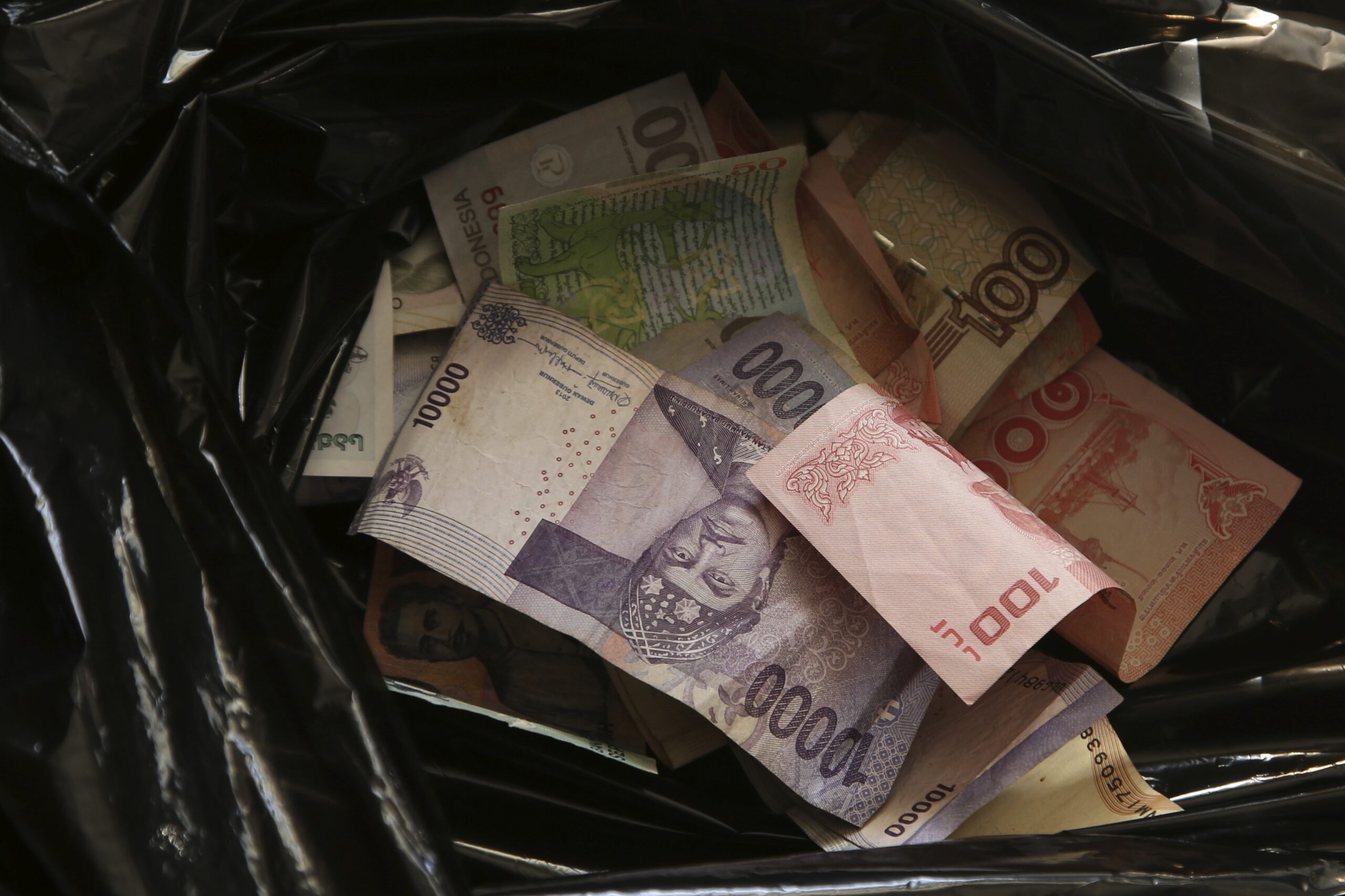 A high angle closeup shot of cash money in a black trash bag